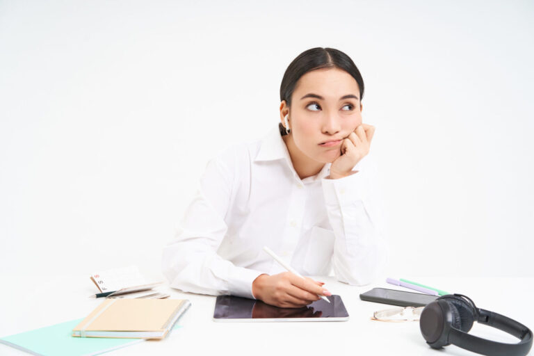 Tired and bored korean woman in office, employee sits with digital tablet, listens music in earphones and looks tired, white background